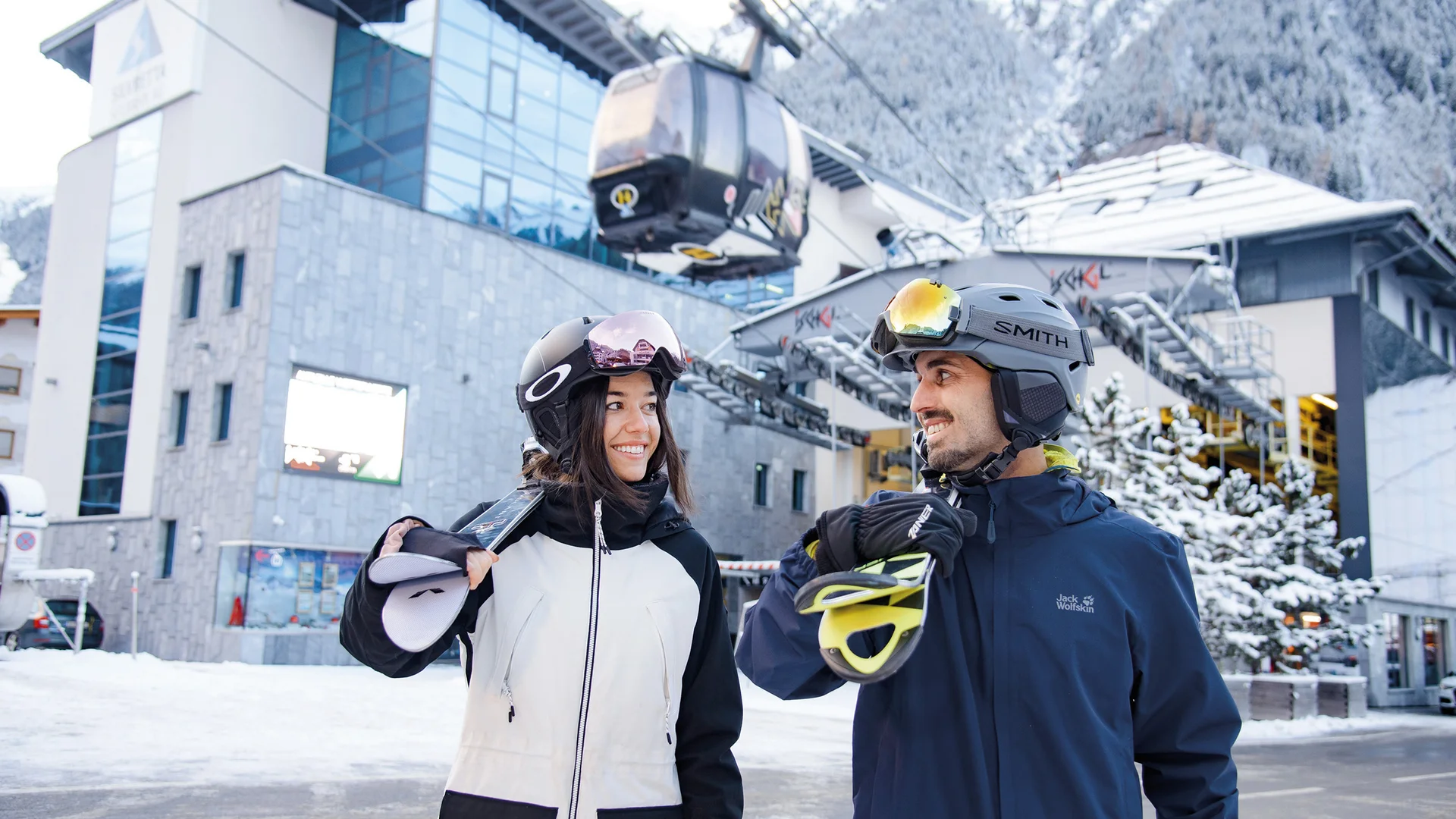 Ferienglück und Alpenland | Ihre stilvollen Hotels in Ischgl Zwei Skifahrer mit Helmen vor einer Seilbahnstation im verschneiten Skigebiet