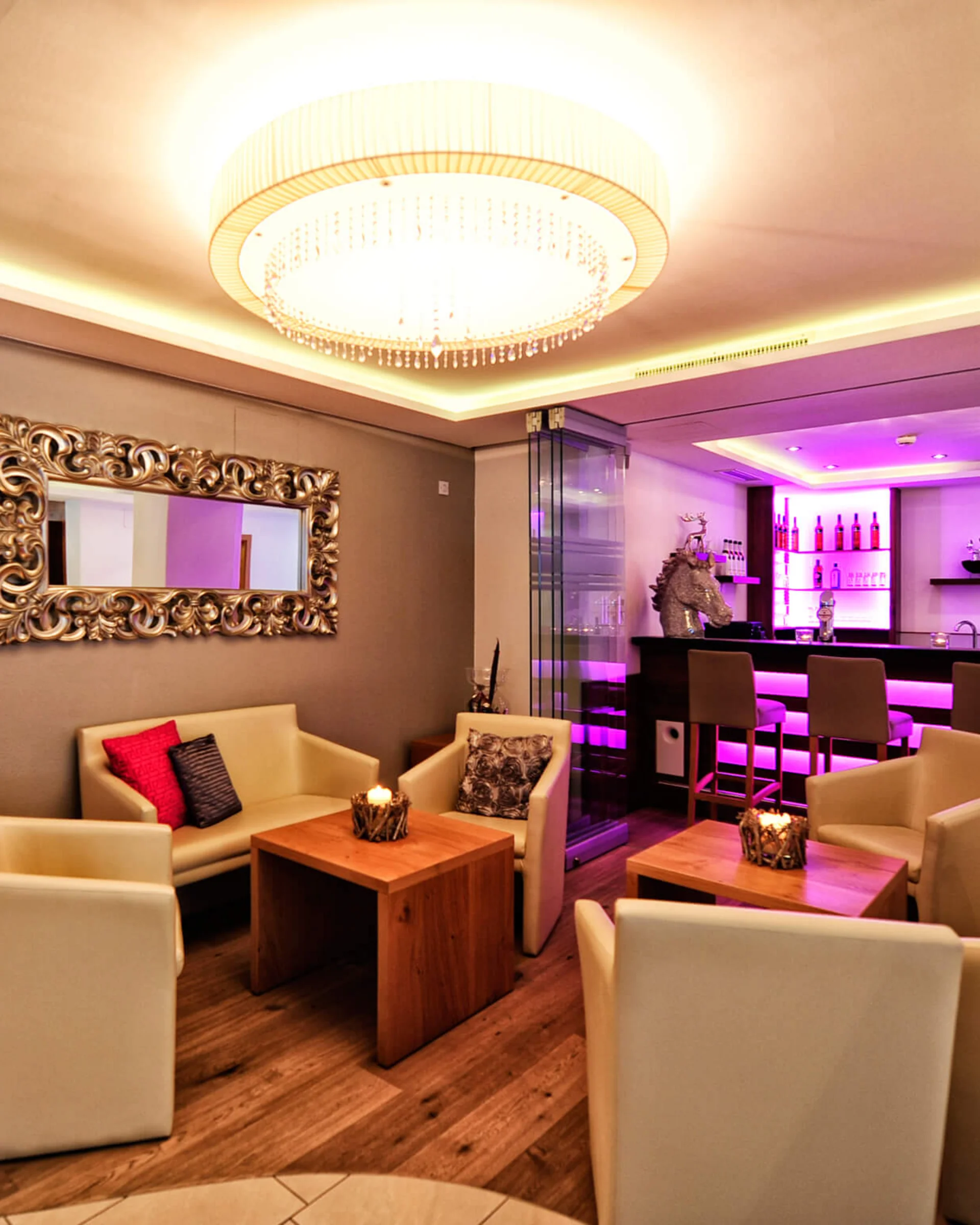 Ferienglück und Alpenland | Ihre stilvollen Hotels in Ischgl Elegante Hotellounge mit Sitzgruppen, Kronleuchter und beleuchtetem Barbereich