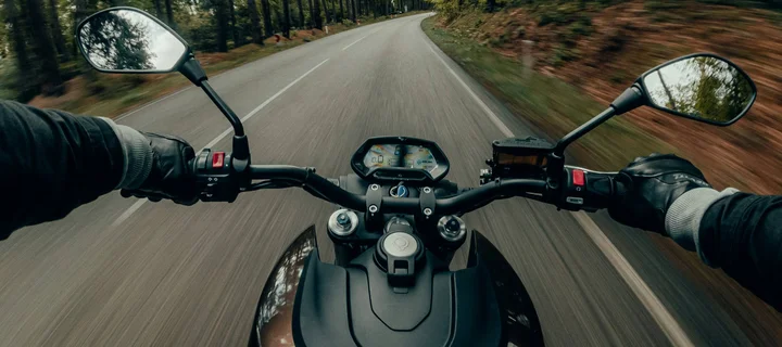 Ferienglück und Alpenland | Ihre stilvollen Hotels in Ischgl Blick vom Motorrad auf eine kurvige Straße durch einen Wald
