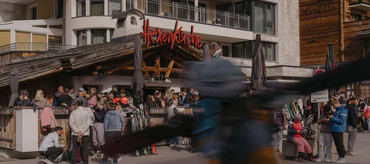 Ferienglück und Alpenland | Ihre stilvollen Hotels in Ischgl Menschen vor der Hexenküche und dem Hotel Ferienglück