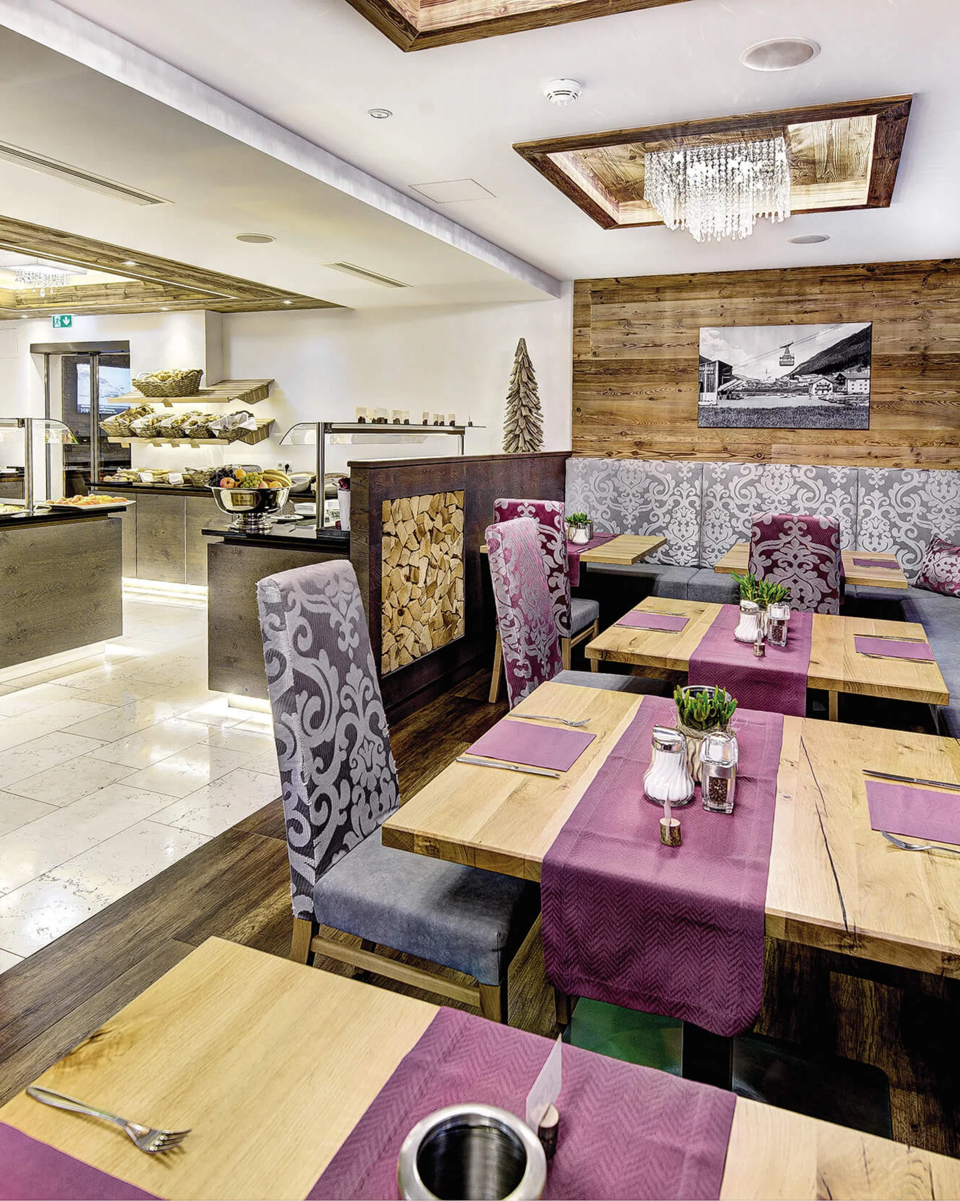 Ferienglück und Alpenland | Ihre stilvollen Hotels in Ischgl Rustikales Restaurant mit Kamin, Holztischen und gemusterten Sitzbänken