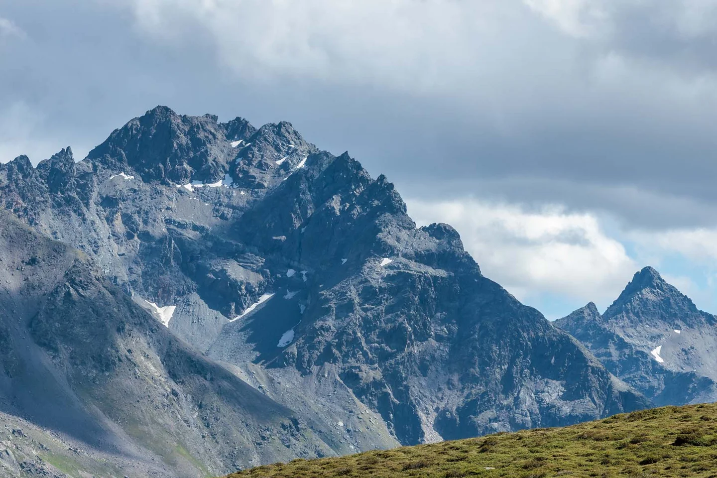 Ferienglück und Alpenland | Ihre stilvollen Hotels in Ischgl Wanderer auf einem Bergweg vor einer schroffen, teils verschneiten Bergkulisse