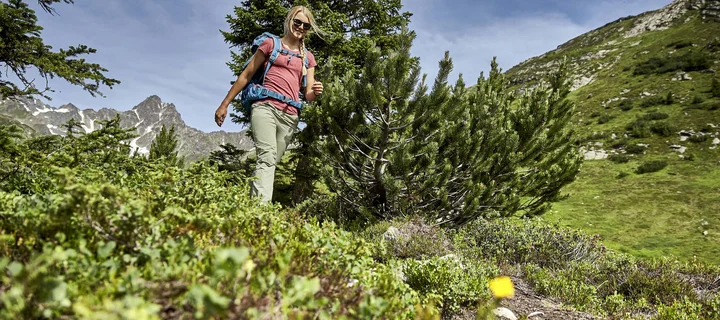 Ferienglück und Alpenland | Ihre stilvollen Hotels in Ischgl Wanderin mit Rucksack in alpiner Landschaft vor felsigen Bergen